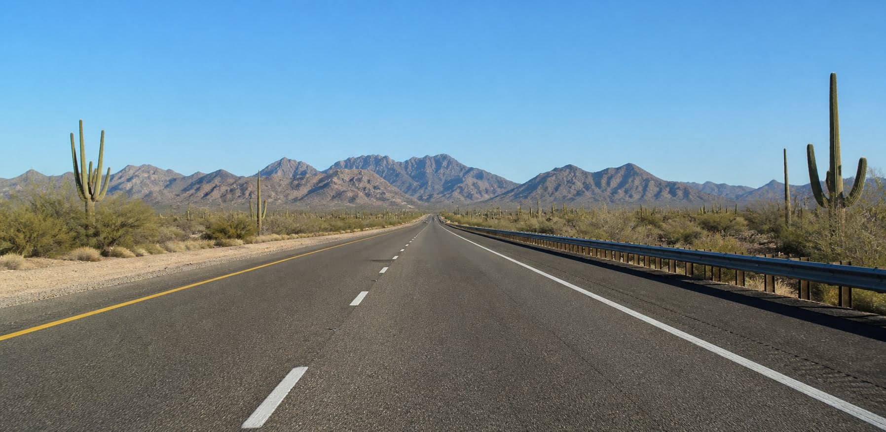 Carretera I-10 abierta cruzando el desierto de Arizona bajo montañas escarpadas